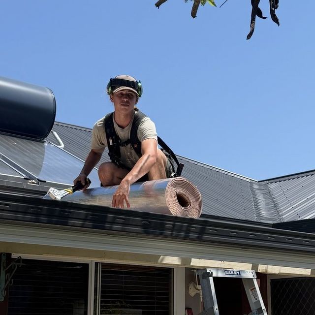 Carpenter on the roof with a roll of sarking before the sheets go on