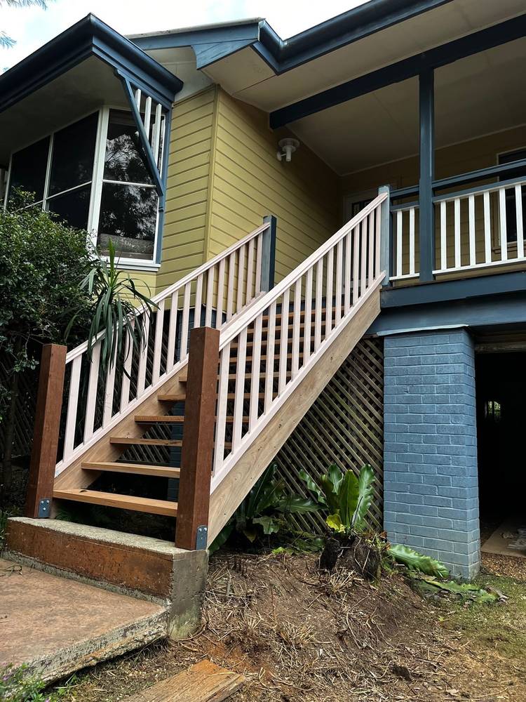 New timber stairs with a white balustrade up to a house deck