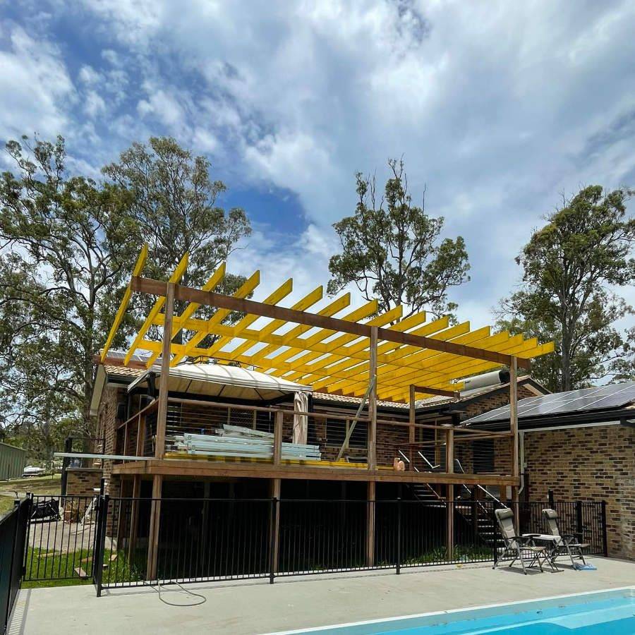 Timber pergola frame over a deck beside a pool