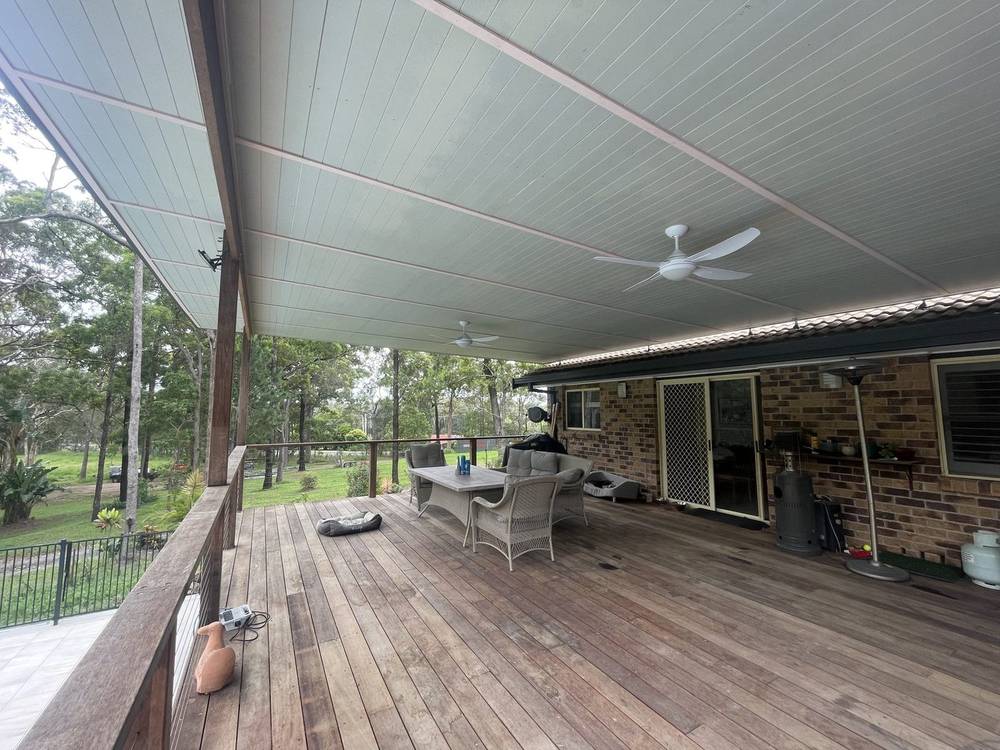 Under a finished covered deck with a lined roof and ceiling fan